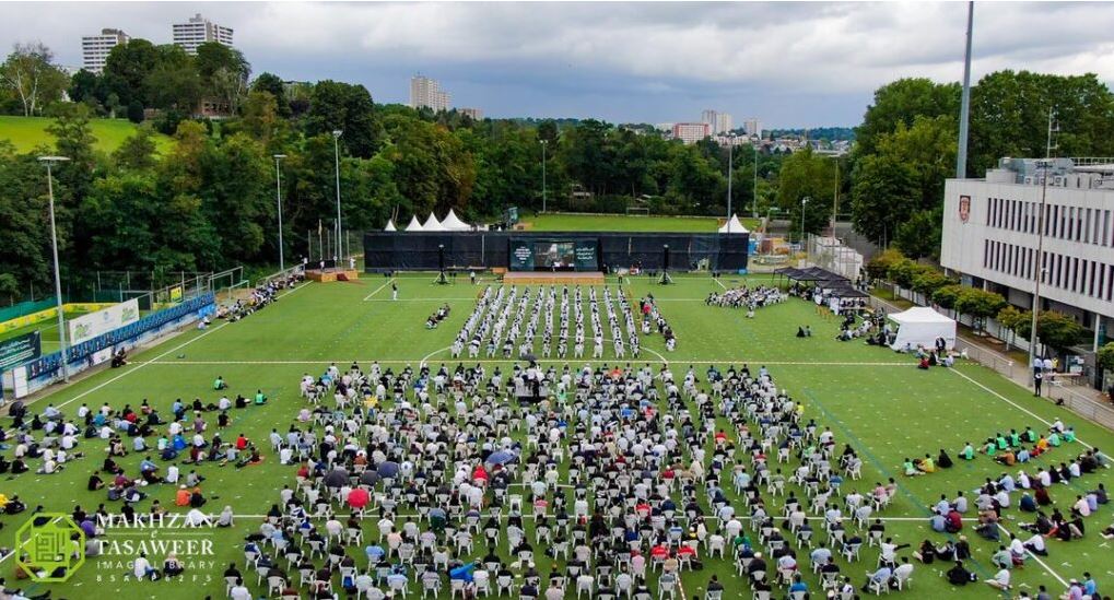 Devotees of Khilafat Sit Unmoved in Pouring Rain as they Smile and Enjoy the Honour of a Virtual Meeting with their Beloved Imam at Germany’s National Ijtema
